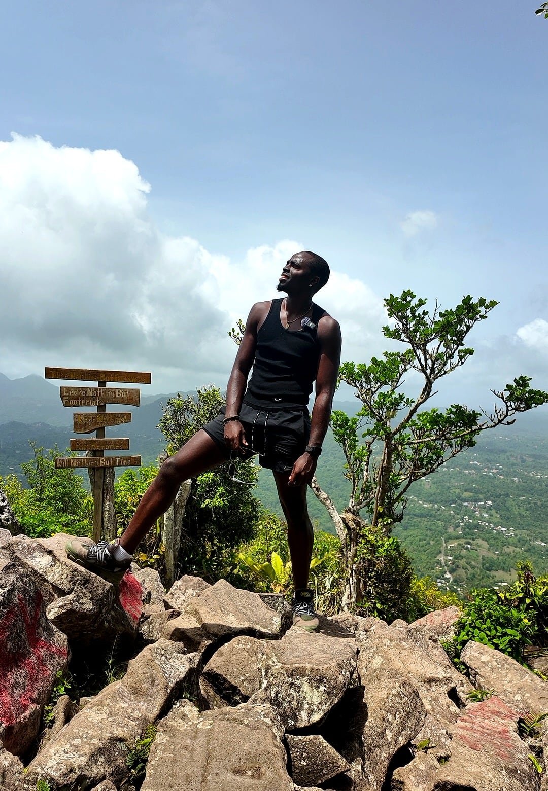 Ian on a mountain summit above green hills and the coast